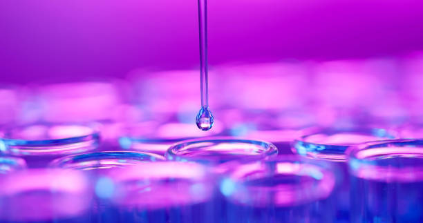 close up of science lab research test tube - pipette dripping droplets to dropper surrounded by neon reflection